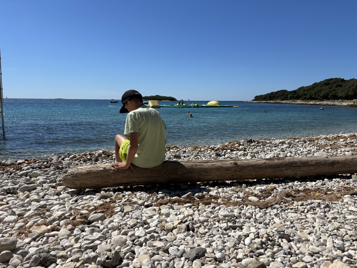 Alex nach dem Schwimmen im Meer vertieft ins Handy